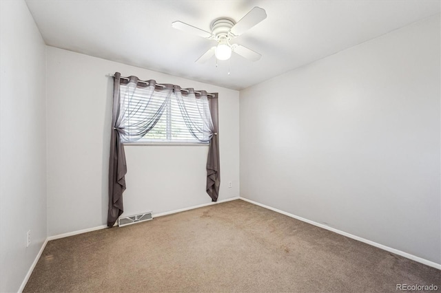 carpeted spare room with a ceiling fan, visible vents, and baseboards