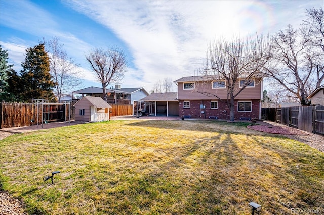 back of house with an outbuilding, a fenced backyard, a patio area, a lawn, and brick siding