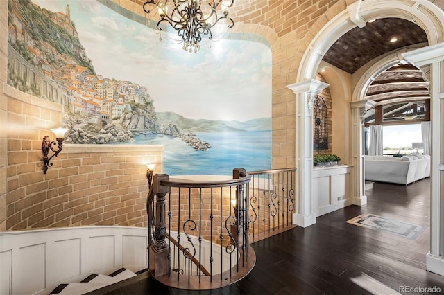 hallway with brick ceiling, ornate columns, dark hardwood / wood-style floors, a chandelier, and lofted ceiling