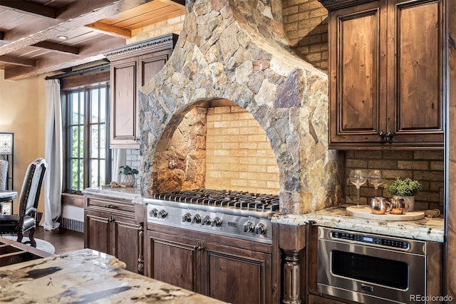 kitchen featuring light stone counters, beam ceiling, stainless steel appliances, and tasteful backsplash