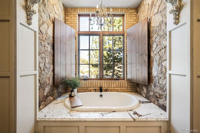 bathroom featuring a chandelier and a tub to relax in