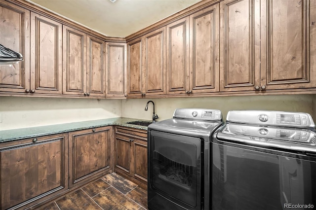 clothes washing area featuring sink, washer and clothes dryer, and cabinets