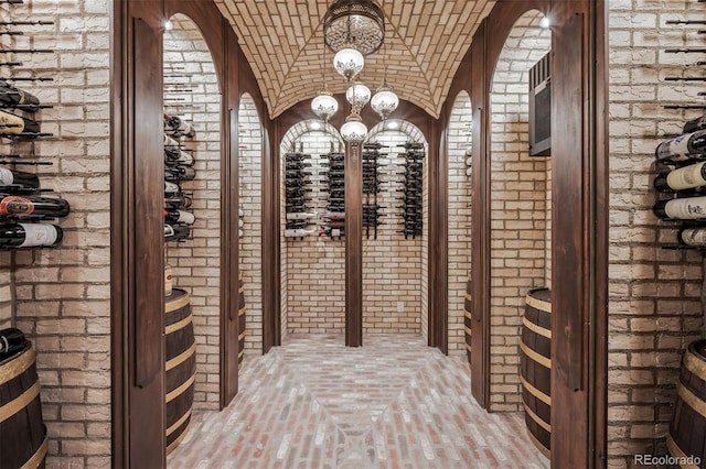 wine cellar with brick wall, brick ceiling, lofted ceiling, and a notable chandelier