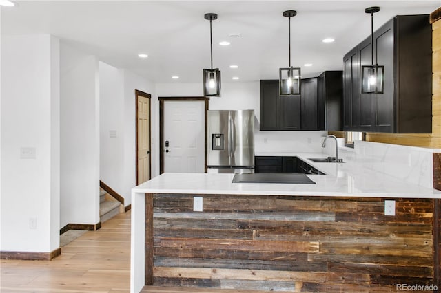 kitchen featuring sink, stainless steel fridge, decorative light fixtures, kitchen peninsula, and light wood-type flooring