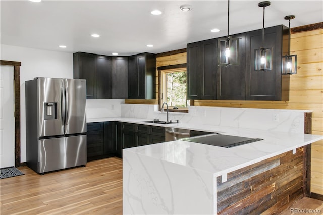 kitchen featuring hanging light fixtures, appliances with stainless steel finishes, light stone counters, and kitchen peninsula