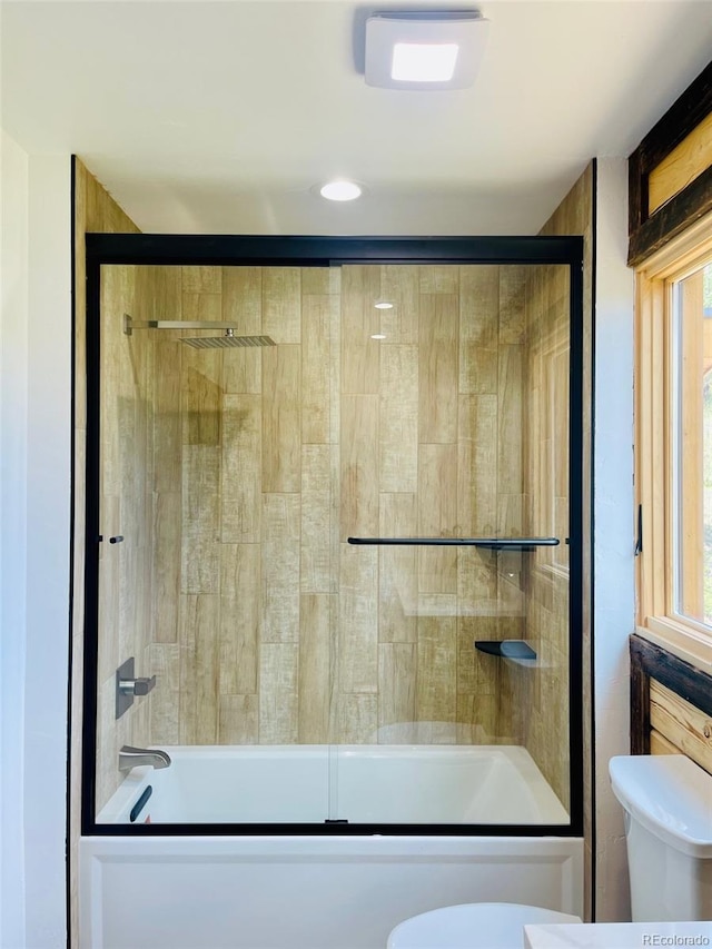 bathroom with combined bath / shower with glass door, plenty of natural light, and toilet