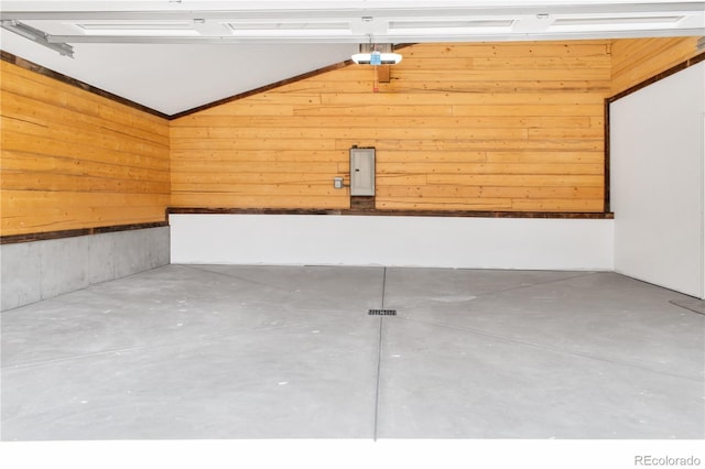 garage with a garage door opener, electric panel, and wood walls