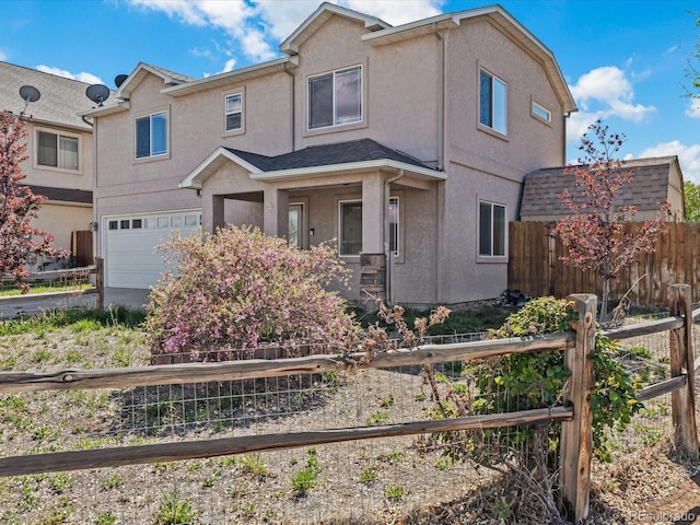 view of front of home with fence, a garage, and stucco siding