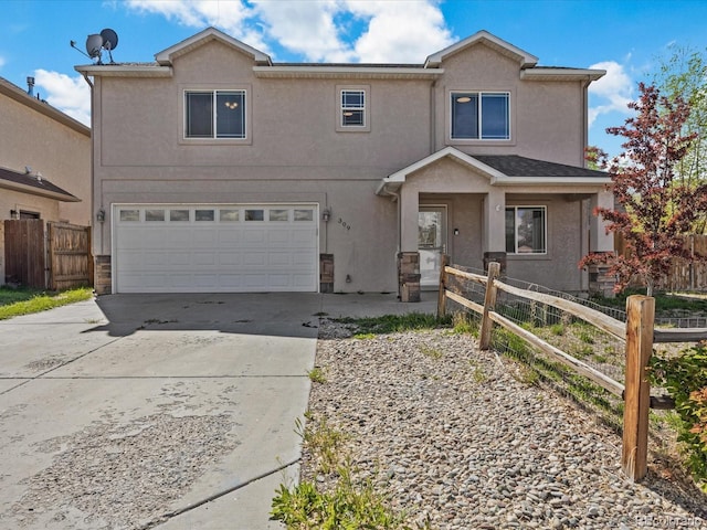 traditional home with stucco siding, fence, driveway, and a garage