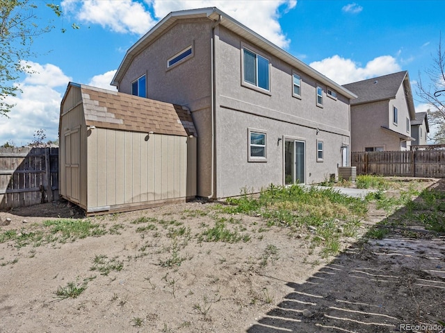 rear view of house featuring fence, an outbuilding, and a shed