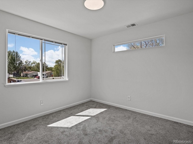 empty room featuring carpet floors, visible vents, and baseboards