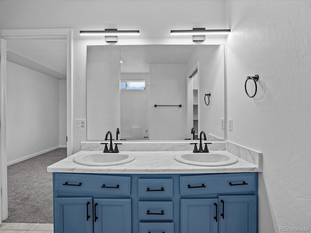 bathroom with a textured wall, a sink, and double vanity