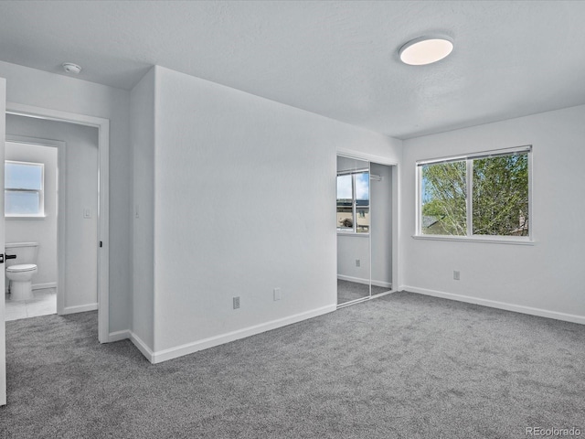 unfurnished bedroom featuring baseboards, carpet flooring, a textured ceiling, and a closet