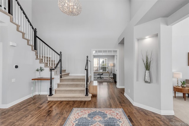 foyer with stairs, dark wood finished floors, and a towering ceiling