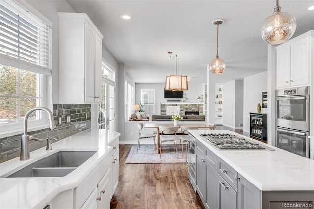 kitchen with stainless steel appliances, dark wood finished floors, a sink, open floor plan, and gray cabinets