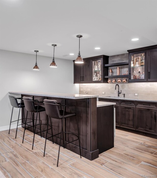 bar with pendant lighting, dark brown cabinetry, and backsplash