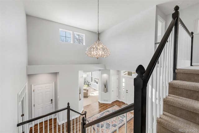 foyer entrance featuring a high ceiling, stairway, a chandelier, and wood finished floors