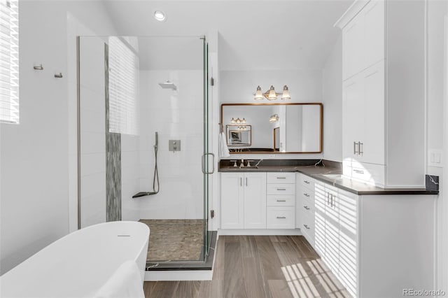 full bathroom with a shower stall, a soaking tub, wood finished floors, and vanity
