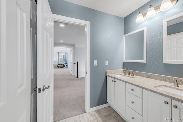 full bathroom featuring a textured wall, double vanity, a sink, and tile patterned flooring