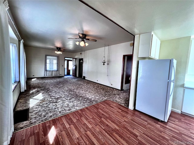 unfurnished living room featuring a ceiling fan, wood finished floors, and carpet flooring