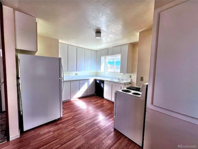 kitchen with white appliances, dark wood-style floors, light countertops, a textured ceiling, and a sink