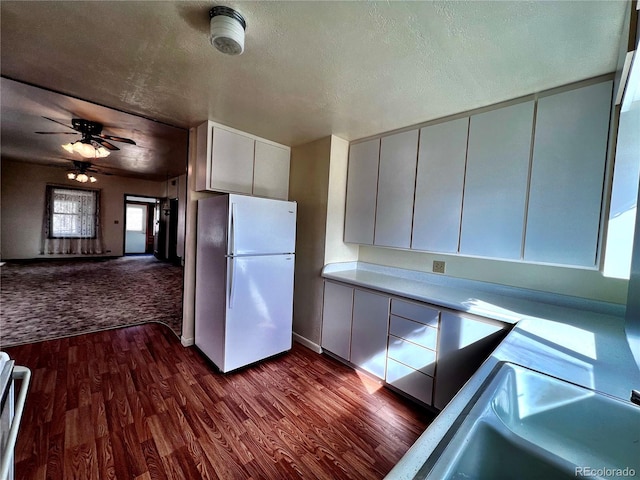 kitchen featuring dark wood-style floors, freestanding refrigerator, light countertops, and a textured ceiling