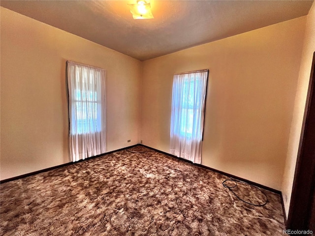 carpeted empty room featuring baseboards