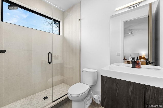 bathroom featuring vanity, a shower stall, toilet, and ceiling fan