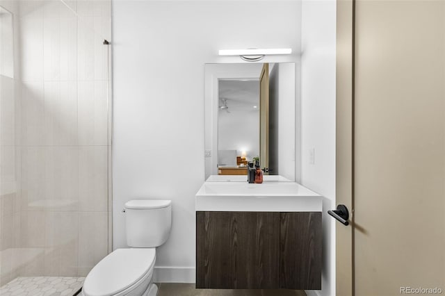 bathroom featuring toilet, vanity, and a tile shower