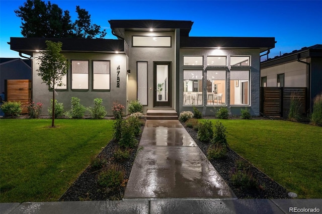 view of front of home featuring stucco siding, a front yard, and fence