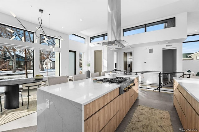 kitchen featuring visible vents, a large island, modern cabinets, island exhaust hood, and stainless steel gas stovetop