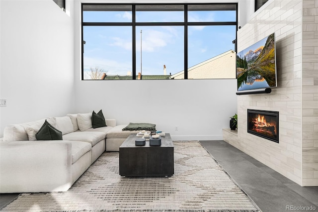 living area with baseboards, finished concrete floors, and a glass covered fireplace