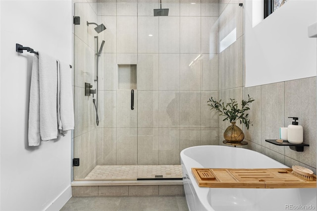 bathroom featuring a stall shower, a freestanding bath, and tile walls