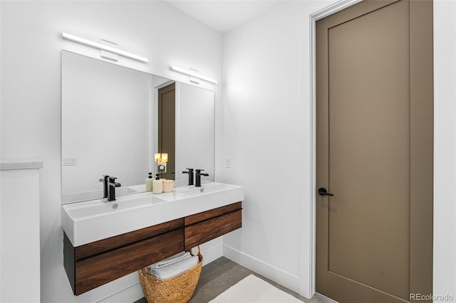 bathroom with double vanity, baseboards, and a sink