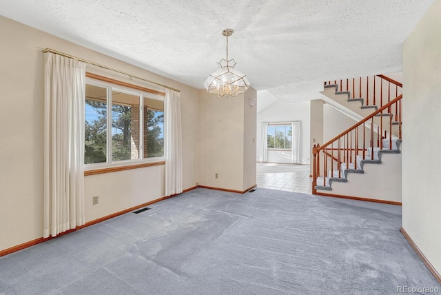 spare room with vaulted ceiling, a textured ceiling, a chandelier, and carpet