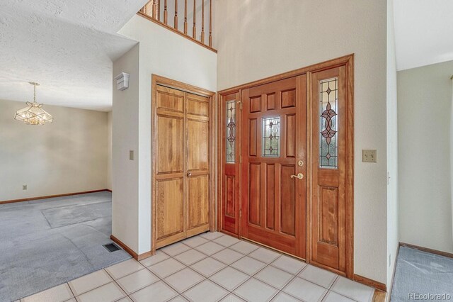 tiled foyer entrance with a textured ceiling and a notable chandelier