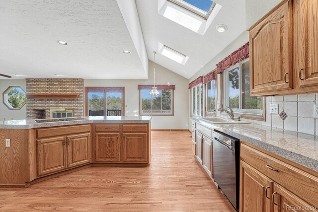 kitchen with backsplash, dishwasher, lofted ceiling with skylight, light hardwood / wood-style flooring, and sink