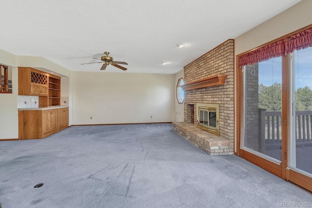 unfurnished living room with light carpet, a brick fireplace, and ceiling fan