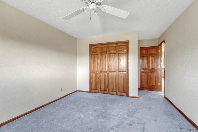 unfurnished bedroom featuring a textured ceiling, light carpet, ceiling fan, and a closet