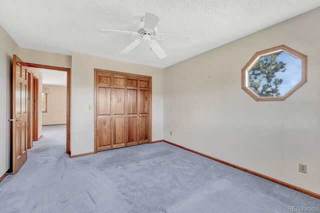 unfurnished bedroom featuring light carpet, a closet, ceiling fan, and a textured ceiling