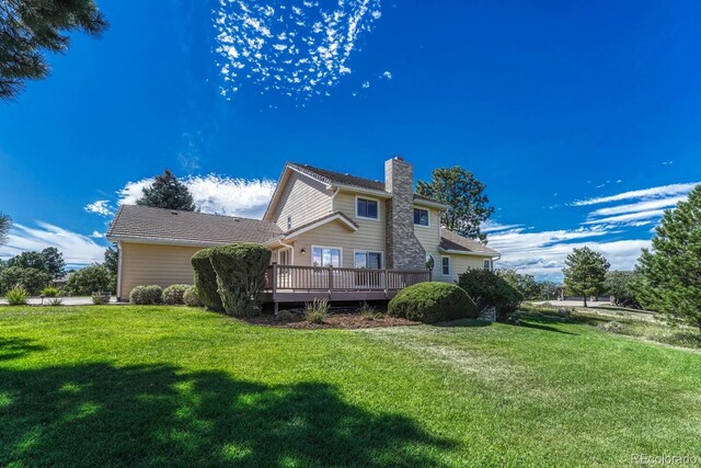 rear view of house featuring a lawn and a deck