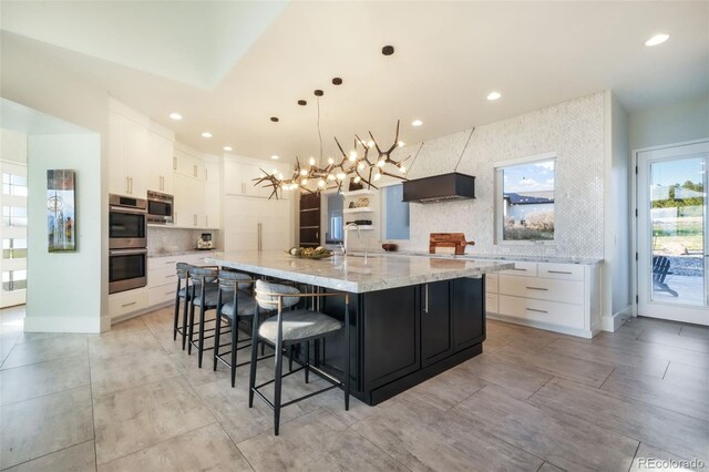 3585 Meadow Run Cir, Colorado Springs, CO 80908 - kitchen featuring appliances with stainless steel finishes, backsplash, white cabinetry, a large island, and a chandelier