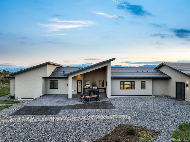 3585 Meadow Run Cir, Colorado Springs, CO 80908 - back of property at dusk with a patio area, stucco siding, and a tile roof
