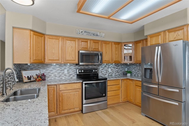 17018 Carr Ave, Parker, CO 80134 - kitchen with appliances with stainless steel finishes, a sink, light wood finished floors, light stone counters, and decorative backsplash