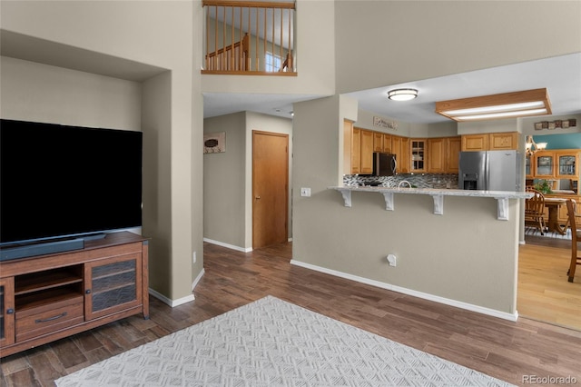 17018 Carr Ave, Parker, CO 80134 - kitchen featuring appliances with stainless steel finishes, wood finished floors, a breakfast bar area, a peninsula, and glass insert cabinets