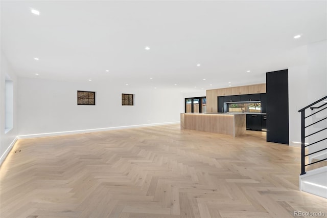 unfurnished living room featuring stairs, recessed lighting, and baseboards