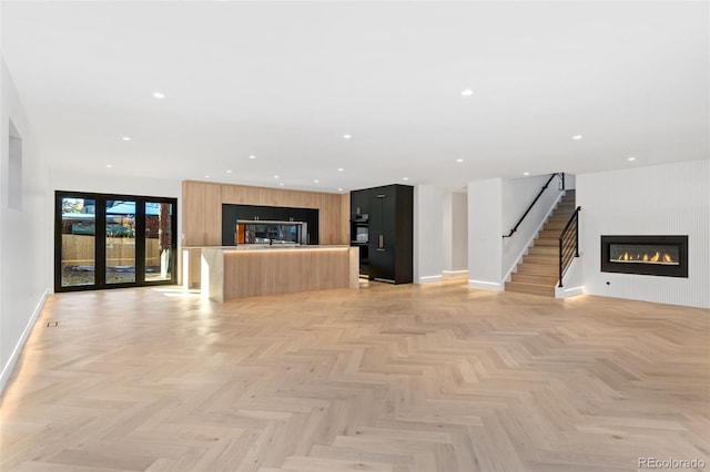 unfurnished living room with stairway, recessed lighting, baseboards, and a large fireplace