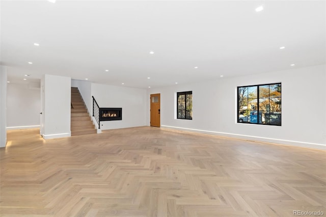 unfurnished living room featuring recessed lighting, baseboards, and a warm lit fireplace