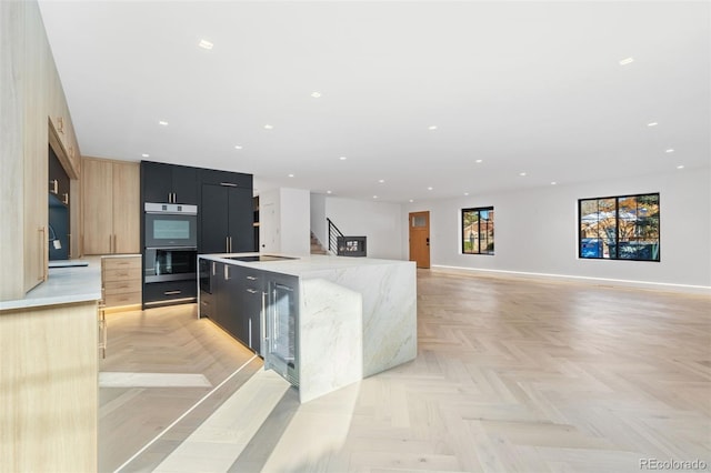 kitchen featuring dark cabinetry, recessed lighting, a large island, double oven, and modern cabinets