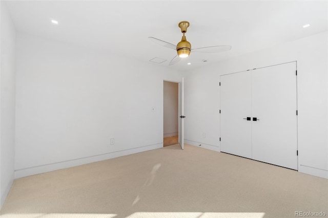 unfurnished bedroom with a closet, light colored carpet, baseboards, and ceiling fan